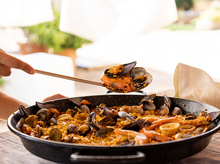 person scooping a seafood paella out of a pan