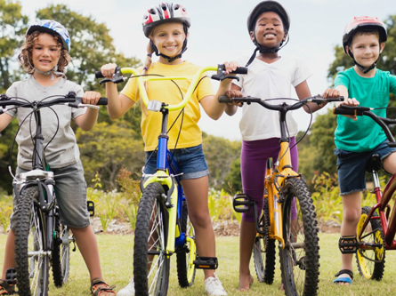several young kids pose on their bikes