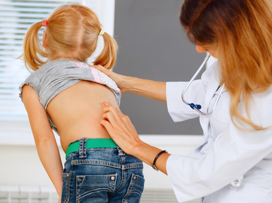 girl bending over to have spine examined in Drs office
