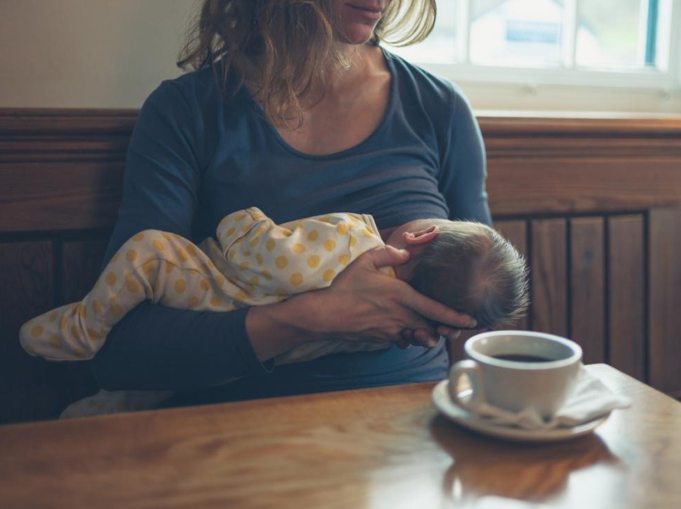 person holding a baby with coffee cup sitting on table