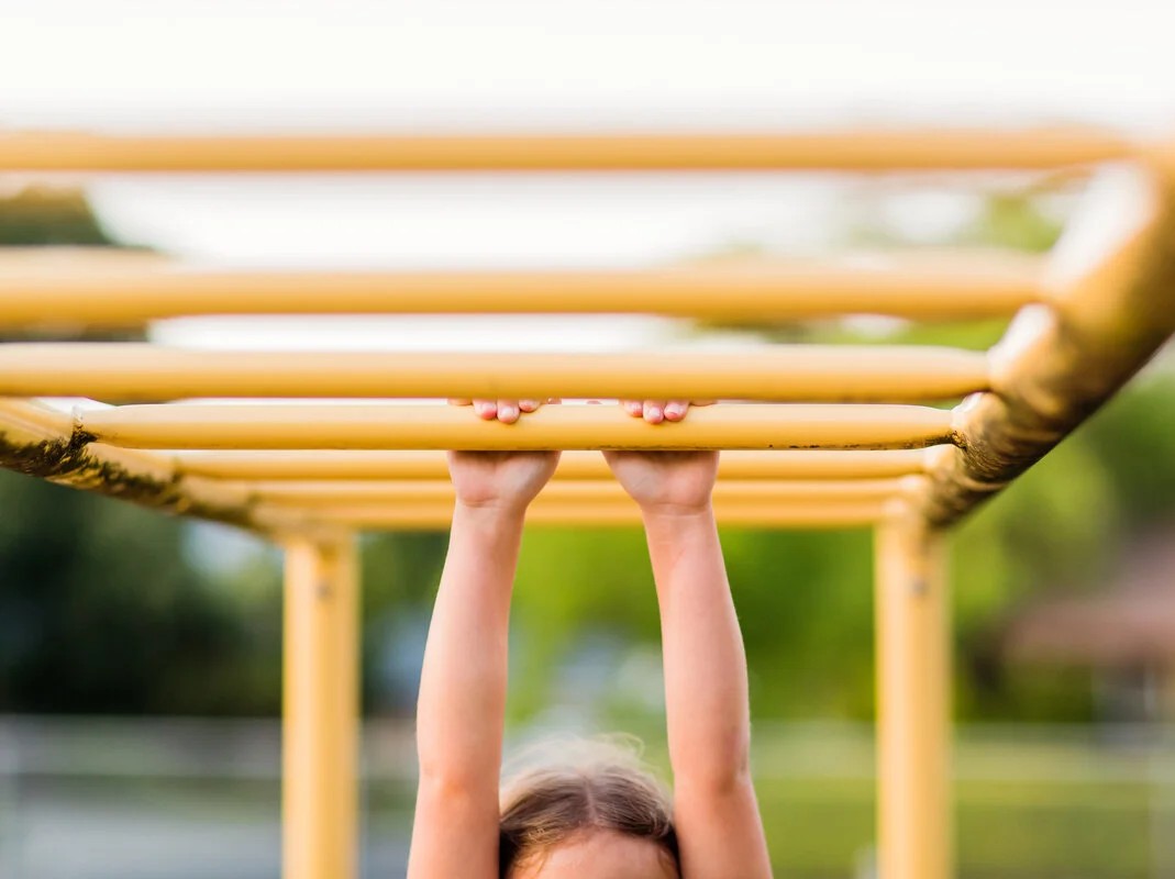 kid holding onto monkeybars