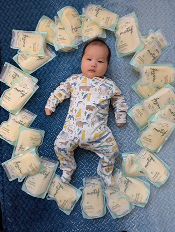 Baby boy surrounded by milk bag donations