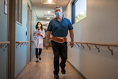 A patient walking down a long hallway.