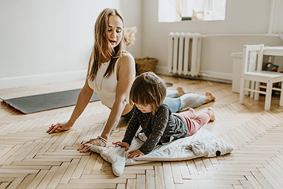 An adult woman and a child doing yoga together.