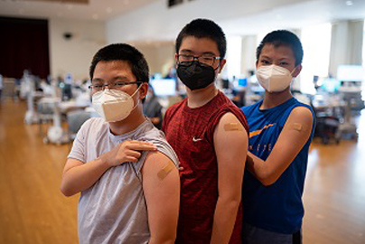 Three young men showing their arms have been vaccinated.
