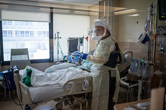 nurse at patient bedside in full PPE