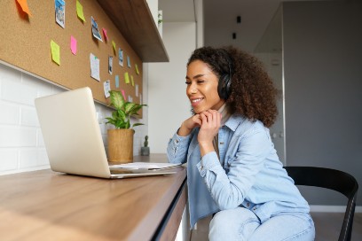 Woman sitting at desk, smiling at her laptop