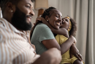 African American family with a dad, mom and daughter, mom and daughter hugging