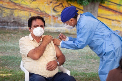 Man in a mask receiving a COVID-19 shot from a health worker
