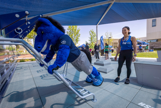 A woman watching the UC Davis Health mascot workout at the fitness court. 