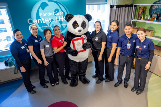 Staff and Panda Cares mascot, Pei Pei, stand for a photo op inside the Panda Cares Center for Hope.