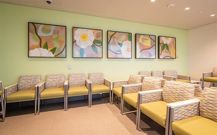 Wide image of Our Camellia Blooms Forever art pieces hanging on the wall of the level 3 northeast waiting area of the 48X Complex.
