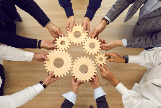 people holding wheel cogs together signifying teamwork