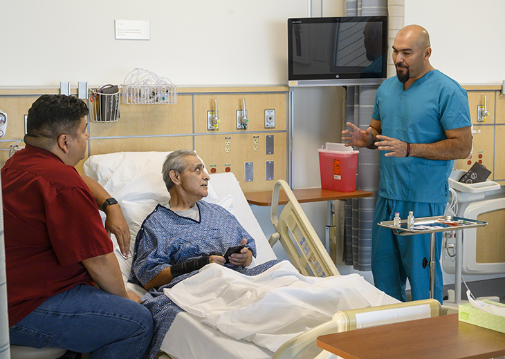 mail nurse provides medication instructions to older adult hospital patient and his family caregiver.