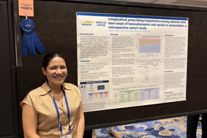 Sylvana Marquina stands next to a research poster marked with a blue ribbon at the Society of Teachers of Family Medicine conference.