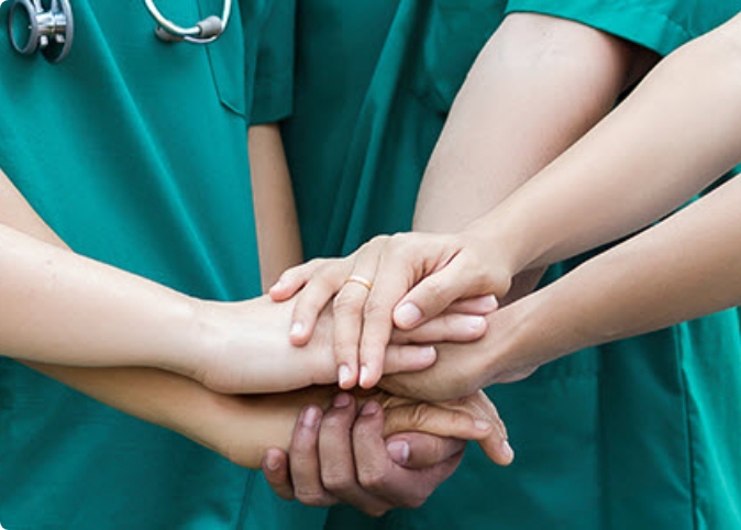 close up of doctors stacking their hands on top of one another
