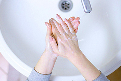 a woman washing her hands over a sink.