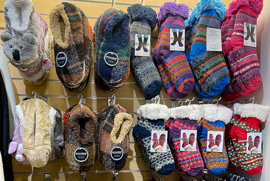 Fuzzy slippers and socks hanging on a display wall.