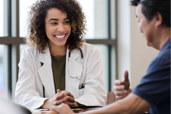 smiling doctor in a white lab coat sitting across from a patient