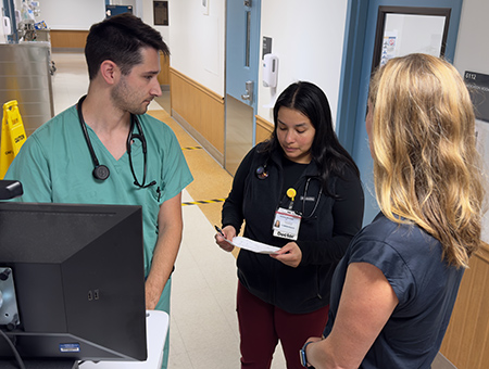 Two TEACH residents discussing a patient&rsquo;s treatment plan in front of their attending physician.