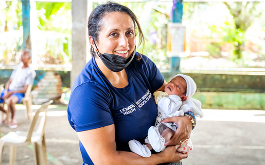 Charleen Singh holding a baby during a recent healthcare outreach visit to the Philippines.