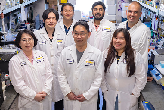 Researcher Yoshihiro Izumiya stands in lab with his team