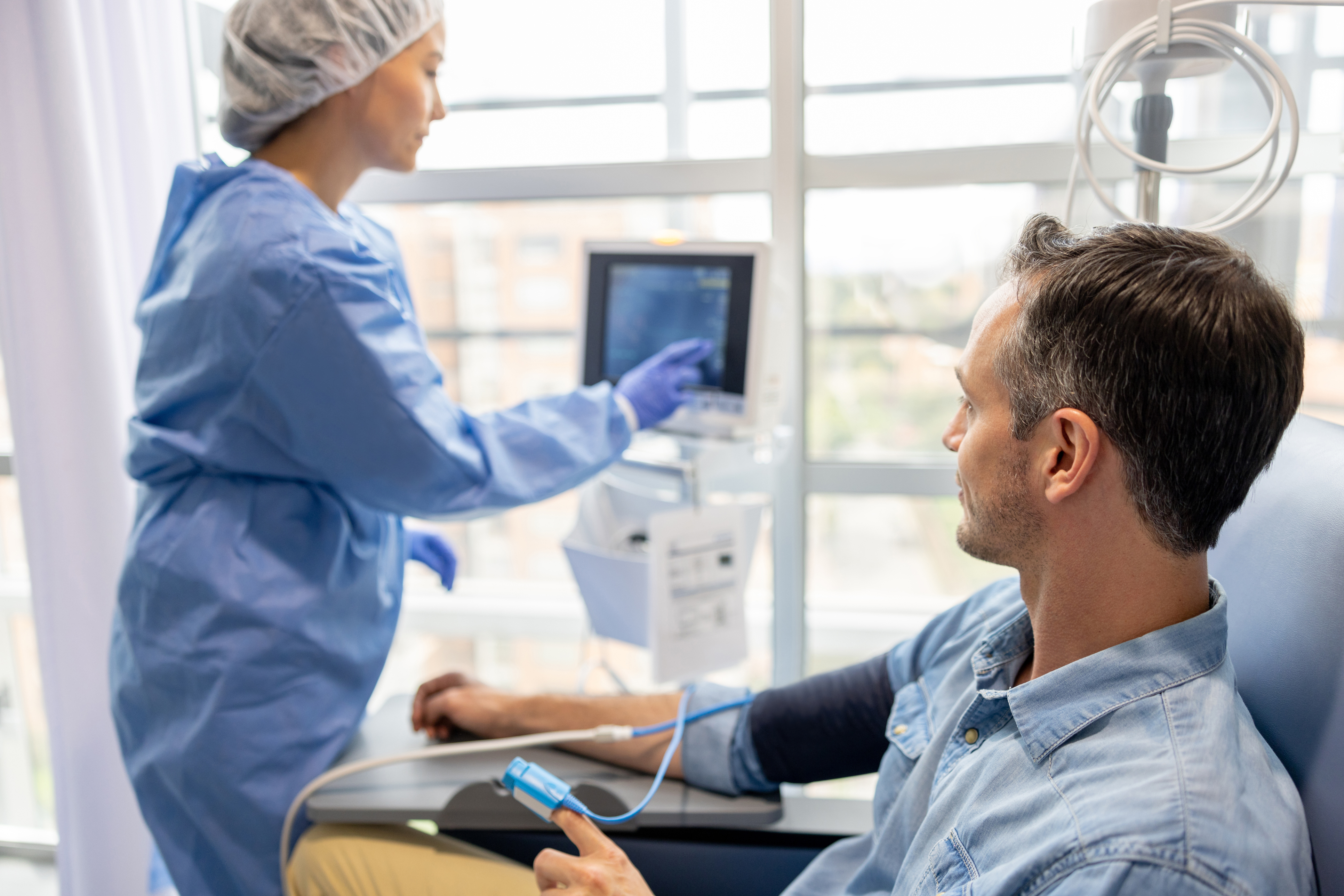 Male patient sitting in chair next to nurse.