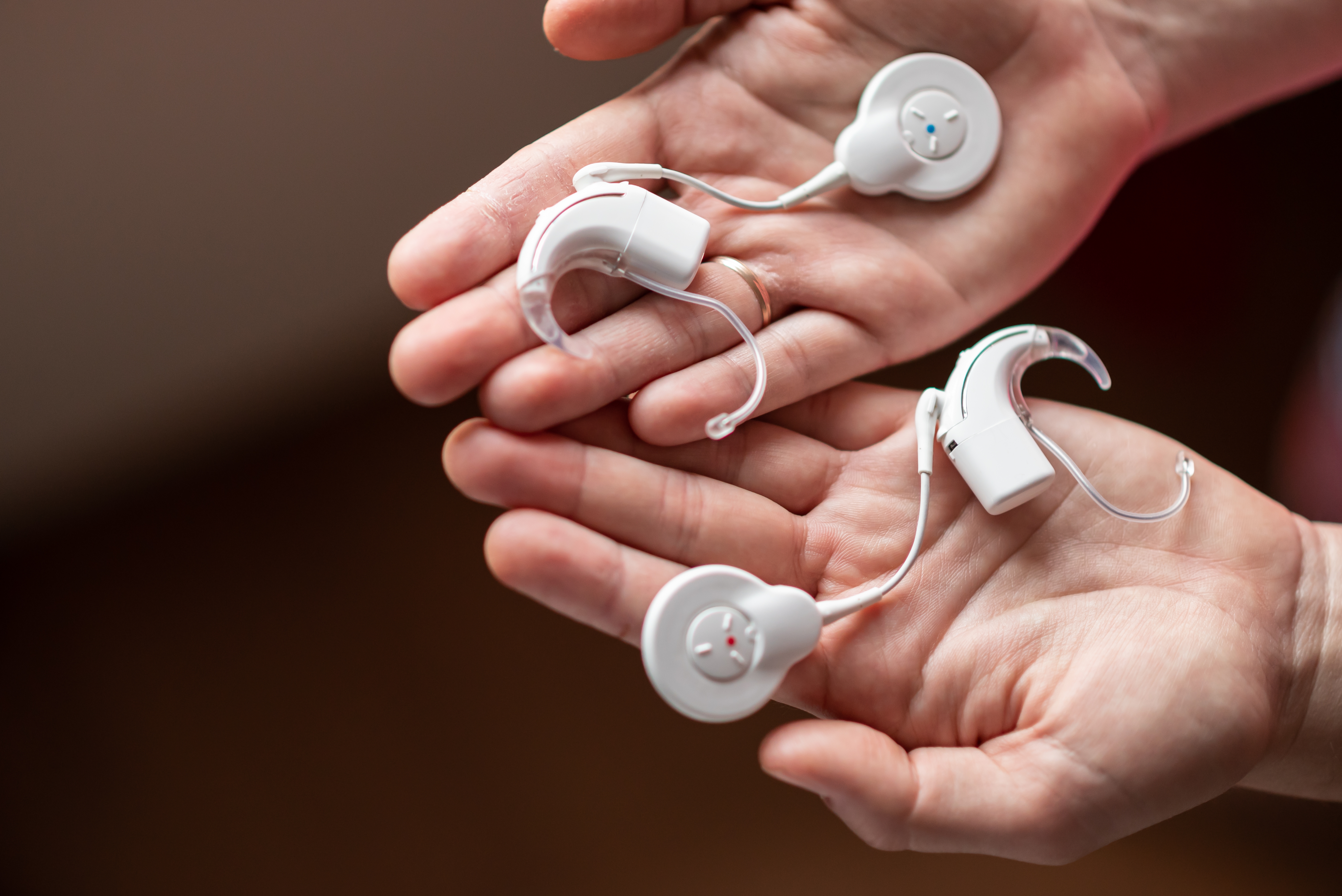 Two hands holding cochlear implants. 