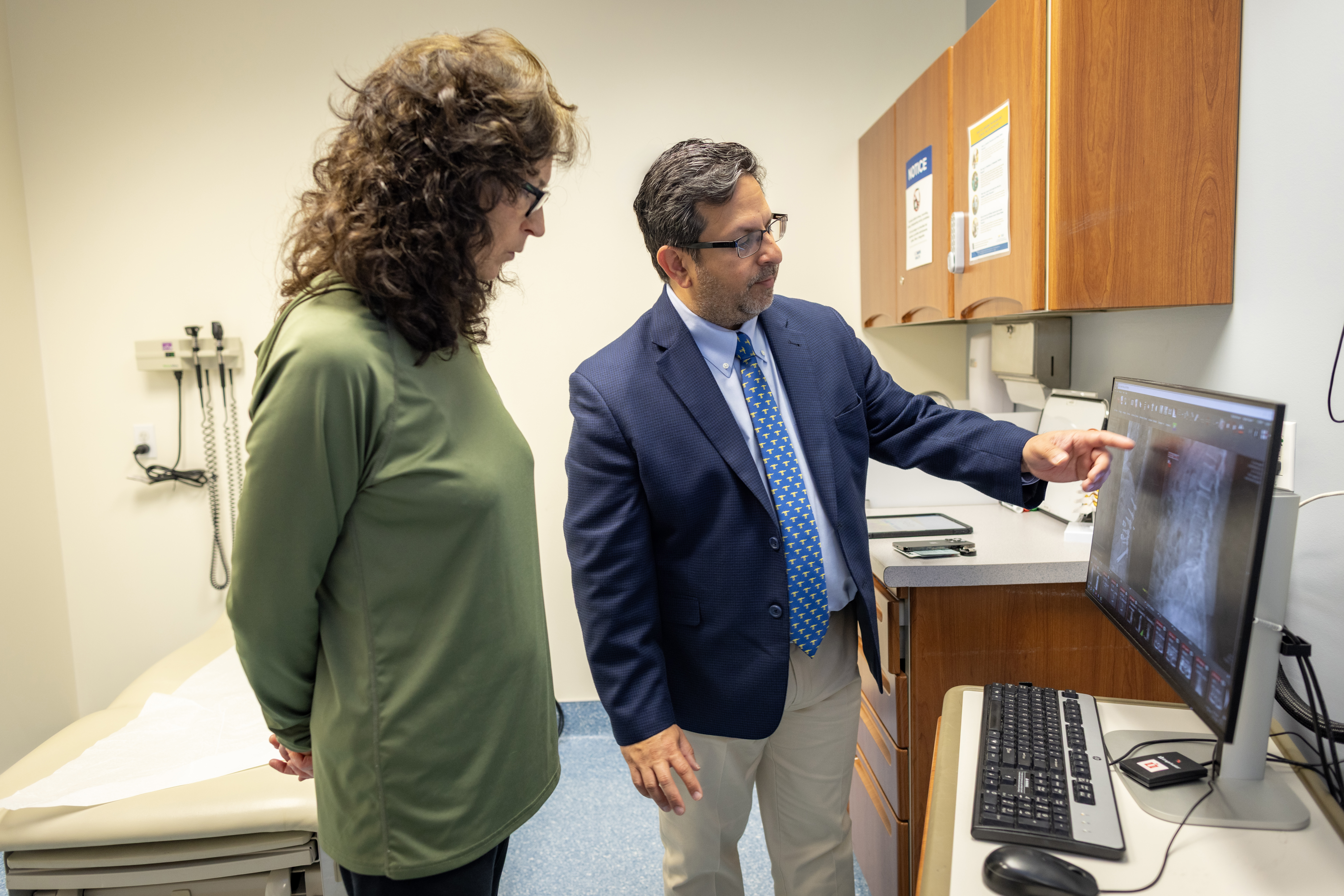 Orthopedic surgeon Safdar Khan and patient looking at xray on screen.