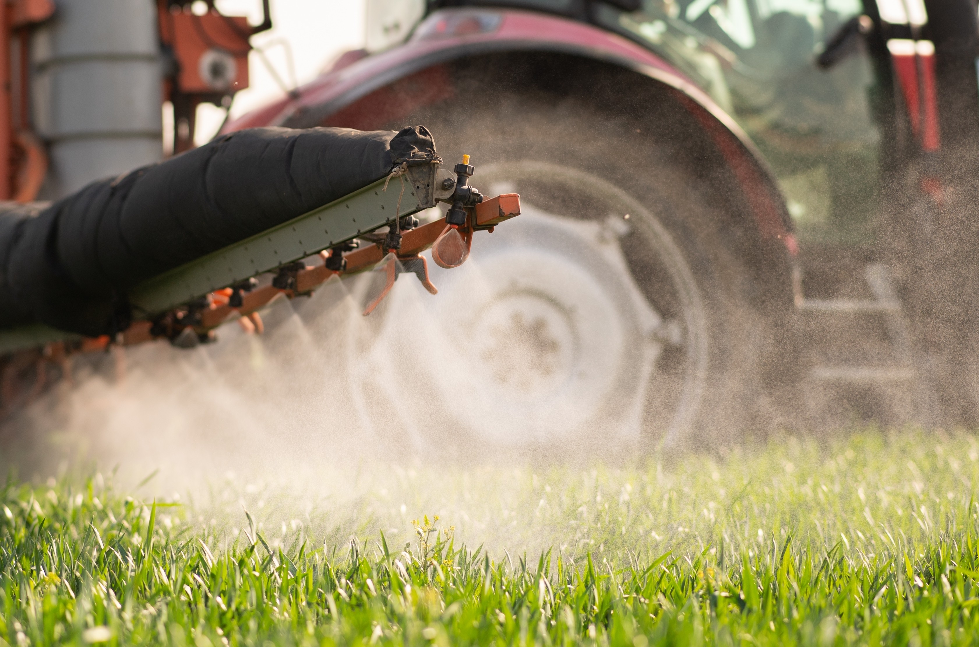 Farm equipment spraying pesticides on grass.