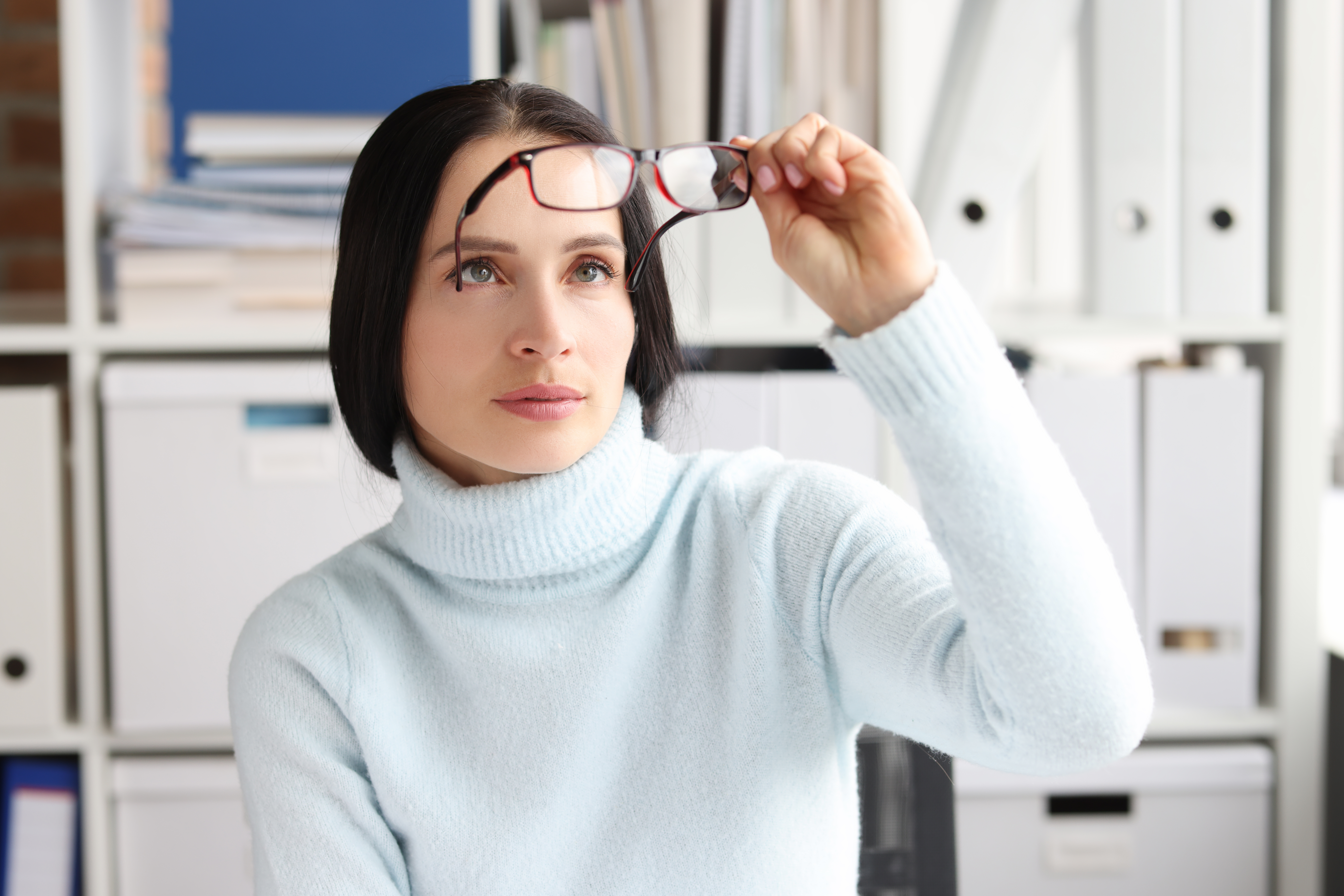 Woman holding glasses away from face.
