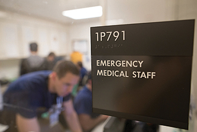 Image of an emergency room sign with staff in the background.