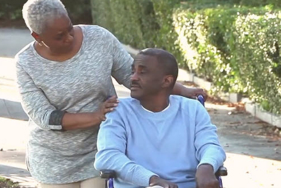A woman helping a man in a wheelchair.