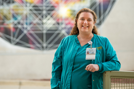 Anna Satake smiles in front of a mural. (c) UC Regents. All rights reserved.