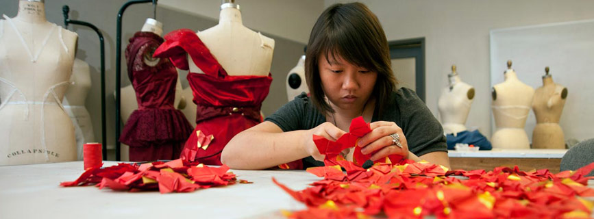 A design student sewing a red dress.