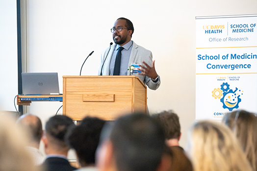 An orator speaking from a podium to a group of people.