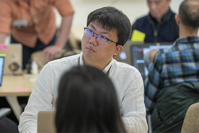 A student sitting with other people looking up at a screen.