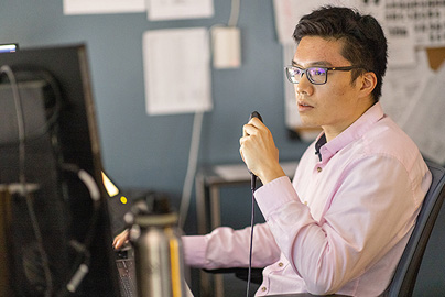 A man sitting at a desk speaking into a small microphone.