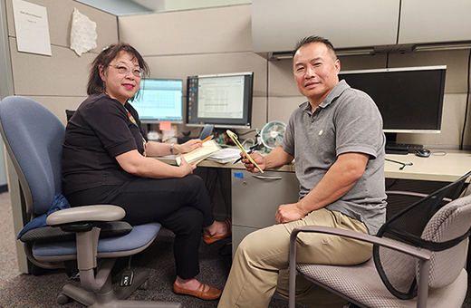 Two colleagues work together at their workstations.