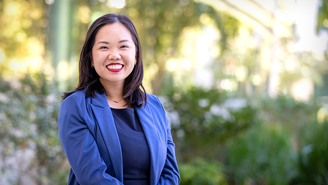 Melody Tran-Reina, M.D. Executive Director, Community Health Scholars, standing outdoors on campus grounds