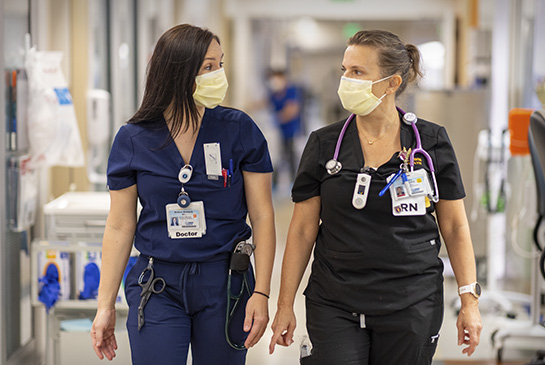 Resident doctor in training walking down hospital hallway with nurse