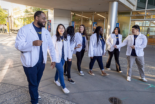 Medical students walking outside on the Sacramento campus, education building in background