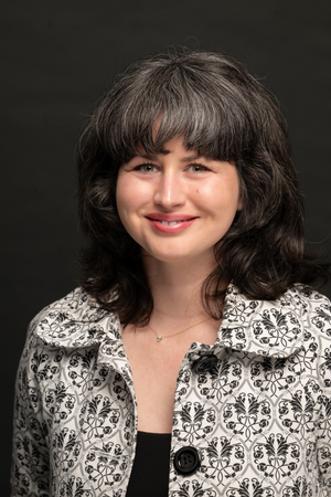 Headshot of Bronwyn Seward Limon. Woman is wearing a black and white coat against a gray background.