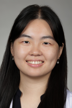 Portrait of medical student Jenny Luu in white coat and smiling.