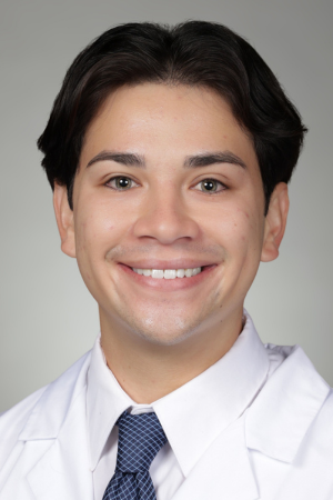 Portrait of medical student Bryce Nguyen in white coat and smiling.