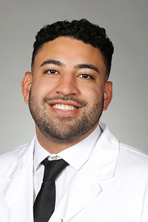 Portrait of medical student Oscar Valdovinos-Varga in white coat and smiling