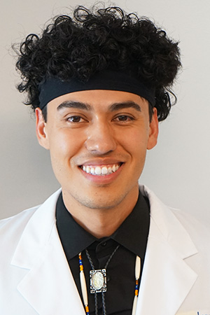 Portrait of medical student Uriah Contreras in white coat and smiling