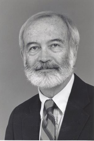 Black-and-white studio portrait of Joe P. Tupin wearing a suit and patterned tie against a plain backdrop.