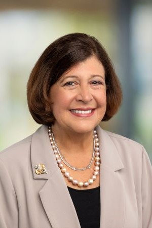 Studio portrait of Lydia Pleotis Howell wearing a light-colored blazer photographed against a indoor background.
