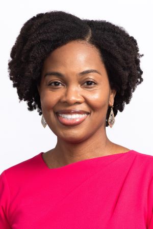 Studio portrait of Ruth Shim wearing a bright pink top, photographed against a plain white background.